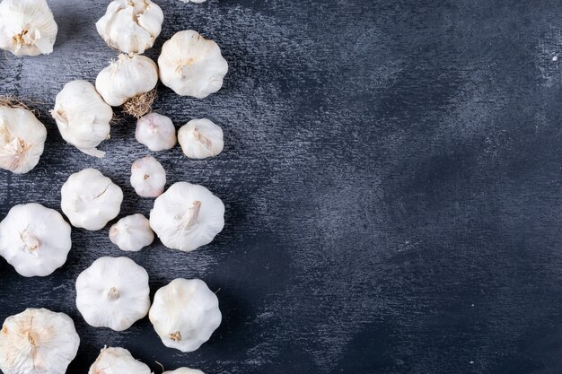 Sommige trossen knoflook aan de linkerkant op donkere getextureerde tafel, bovenaanzicht