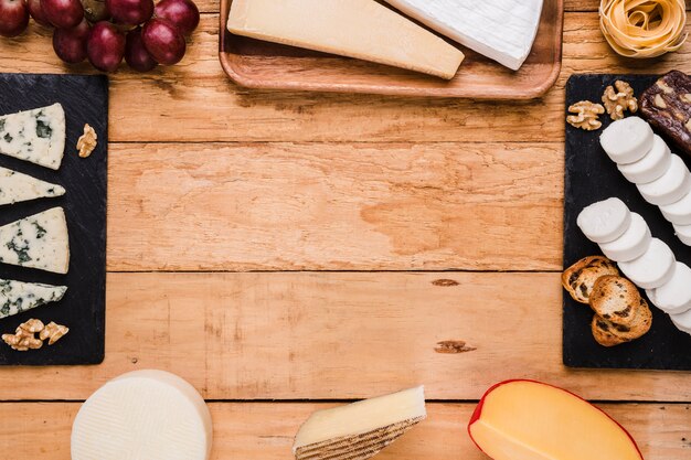 Soorten kaas; druiven; walnoot en pasta gerangschikt in frame over houten oppervlak