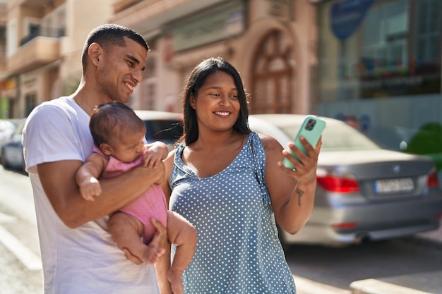 Gratis foto spaanse familie die elkaar omhelst en selfie maakt met een smartphone op straat