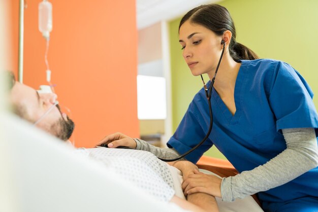 Spaanse vrouwelijke arts die patiënt met stethoscoop onderzoekt in het ziekenhuis