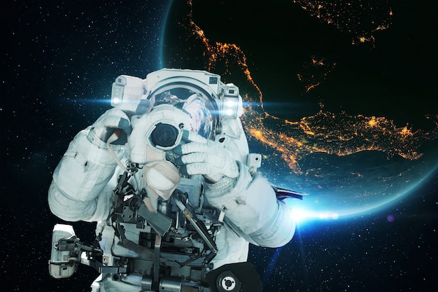 Spaceman-astronaut met een camera maakt een foto in de open ruimte met de blauwe planeet aarde en de lichten van nachtsteden. ruimtemissie en ruimtefotograafconcept