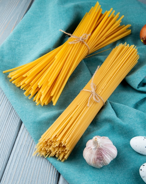 Spaghetti en linguini op het blauwe zijaanzicht van het achtergronduiknoflook