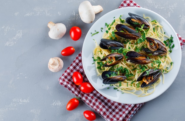 Spaghetti en mossel met tomaten, champignons in een plaat op gips en keuken handdoek