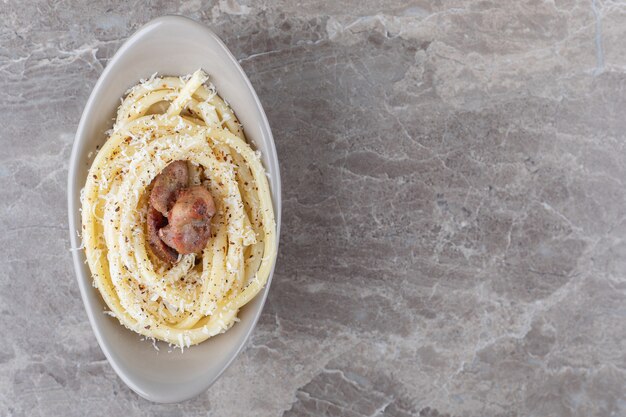 Spaghetti en vlees op de kom, op de marmeren achtergrond.