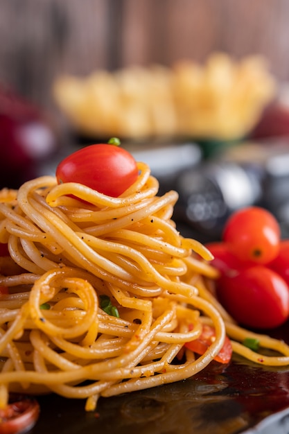 Spaghetti in een zwarte kop met tomaten en sla.