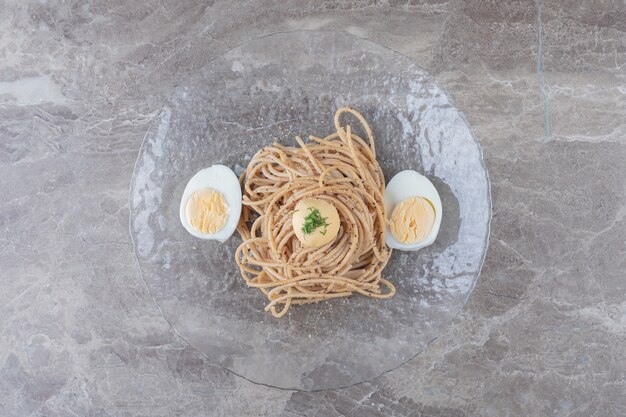 Spaghetti met gekookte eieren op glasplaat.