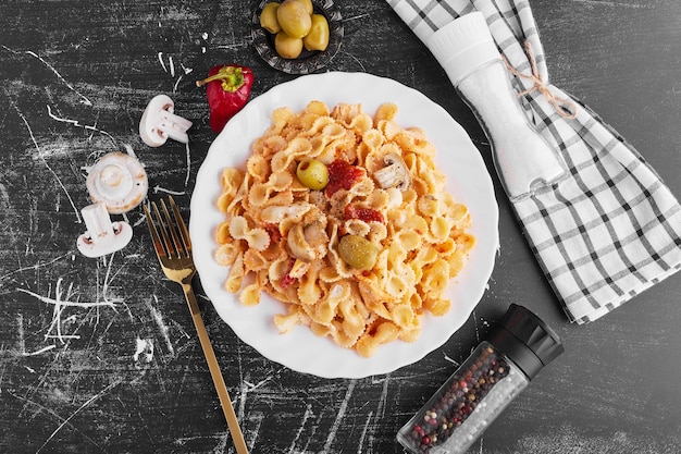 Spaghetti met gemengde ingrediënten in een witte plaat, bovenaanzicht.