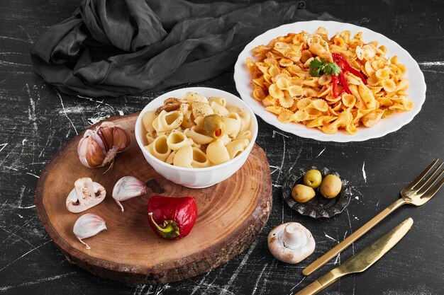 Spaghetti met kruiden en groenten in een witte plaat en pasta in een kopje.