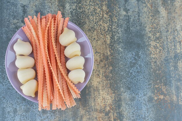 Gratis foto spaghetti met pijppasta's in de kom, op het marmeren oppervlak.