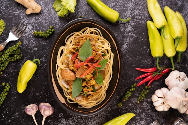 Spaghetti met venusschelpen in een zwarte plaat met pepers Verse knoflook en peper.