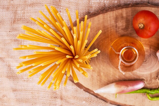 Spaghetti op een houten bord met ingrediënten, bovenaanzicht.