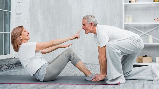 Speels paar dat yogaoefening thuis doet