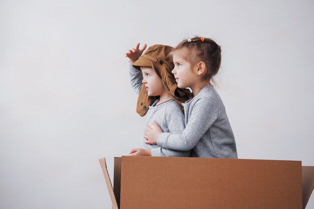 Speelse jeugd. Kleine jongen plezier met kartonnen doos. Jongen die piloot beweert te zijn. Kleine jongen en meisje plezier thuis