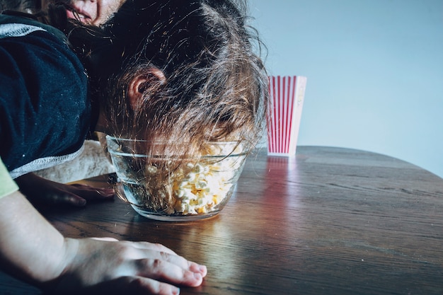 Speelse jongen eten popcorn uit kom