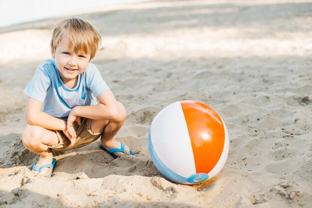 Speelse jongen zit naast wind bal