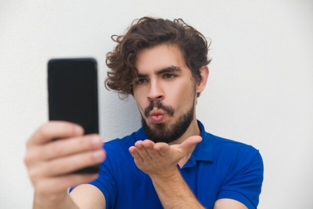 Speelse positieve kerel die selfie op smartphone neemt
