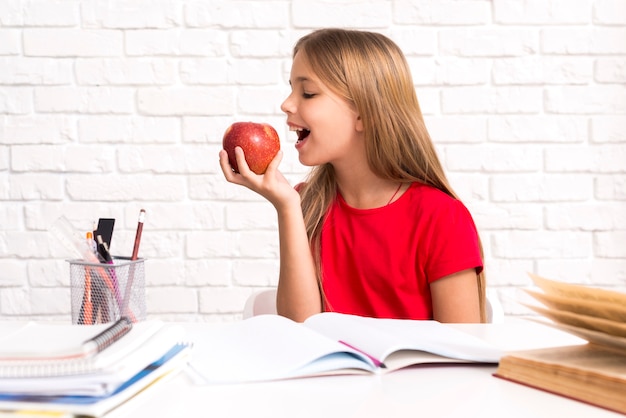 Gratis foto speelse schoolmeisje bijtende appel