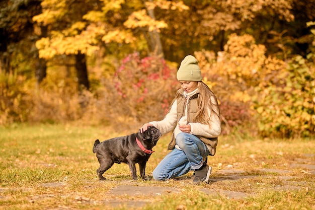 Spelen met een hond. een meisje in warme kleren speelt met een hond in het park