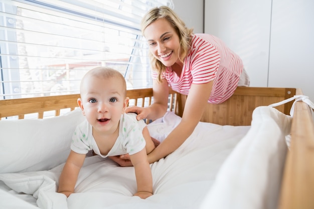 Spelen van de moeder met haar baby jongen in wieg