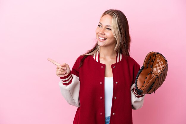 Speler russische vrouw met honkbalhandschoen geïsoleerd op een roze achtergrond die met de vinger naar de zijkant wijst en een product presenteert