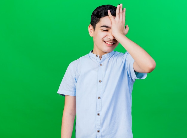 Spijt van jonge blanke jongen hand zetten voorhoofd geïsoleerd op groene achtergrond met kopie ruimte