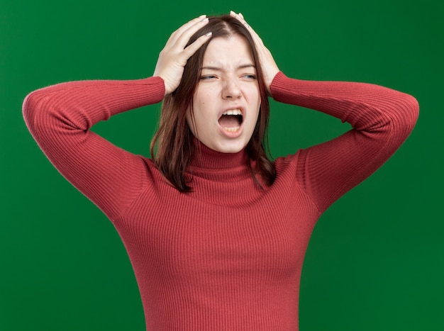 Spijt van jonge mooie vrouw die haar handen op het hoofd houdt en naar de zijkant kijkt