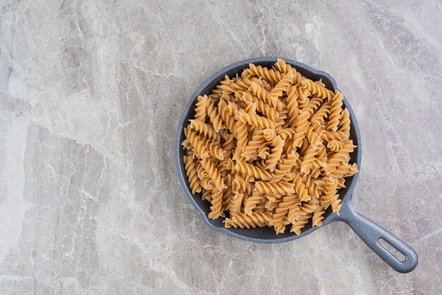 Spiraalvormige zelfgemaakte pasta's in een zwarte pan.