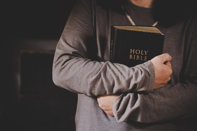 Spiritualiteit en religie, handen gevouwen in gebed op een Heilige Bijbel in kerkconcept voor geloof.