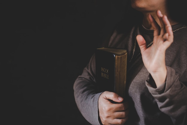 Spiritualiteit en religie, handen gevouwen in gebed op een Heilige Bijbel in kerkconcept voor geloof.