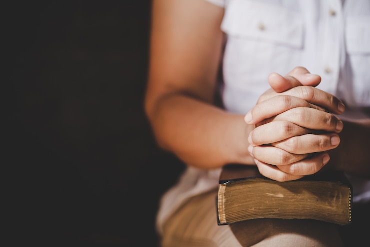 Gratis Foto spiritualiteit en religie, handen gevouwen in gebed over een heilige bijbel in kerk-concept voor geloof.