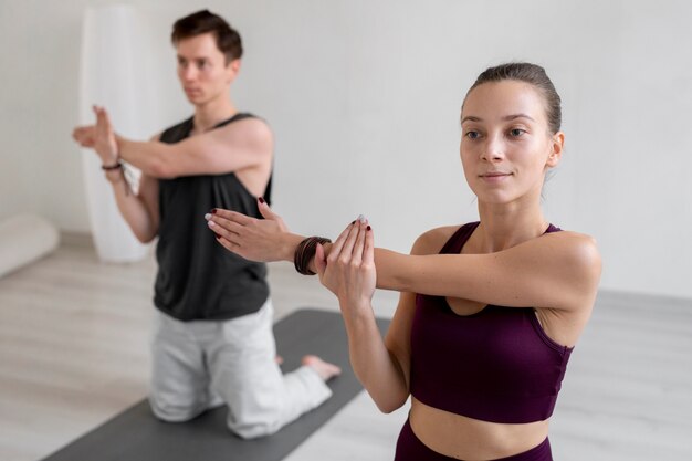 Spirituele jonge man en vrouw die binnen yoga beoefenen