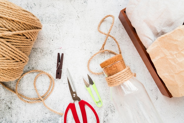 Spoel van jute reeks; wasknijper; schaar en glazen fles met kurk op gestructureerde achtergrond