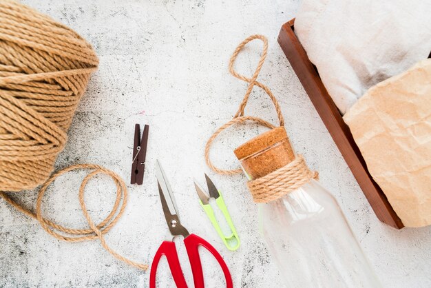 Spoel van jute reeks; wasknijper; schaar en glazen fles met kurk op gestructureerde achtergrond