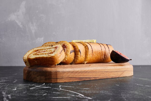 Spons rollcake met chocoladevulling op een houten bord.