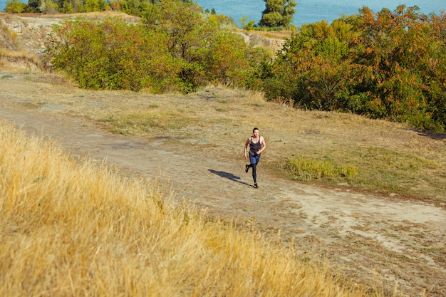 Gratis foto sport hardlopen. man loper sprinten buiten in de schilderachtige natuur.