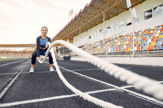 Sport meisje in een blauwe uniforme training in het stadion met touw