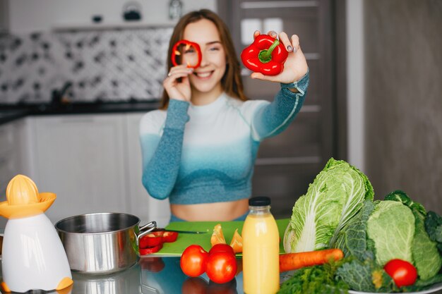 Sportenmeisje in een keuken met groenten