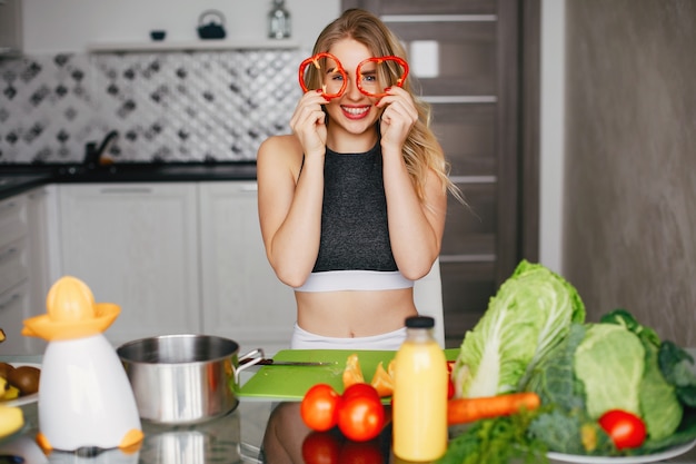 Sportenmeisje in een keuken met groenten