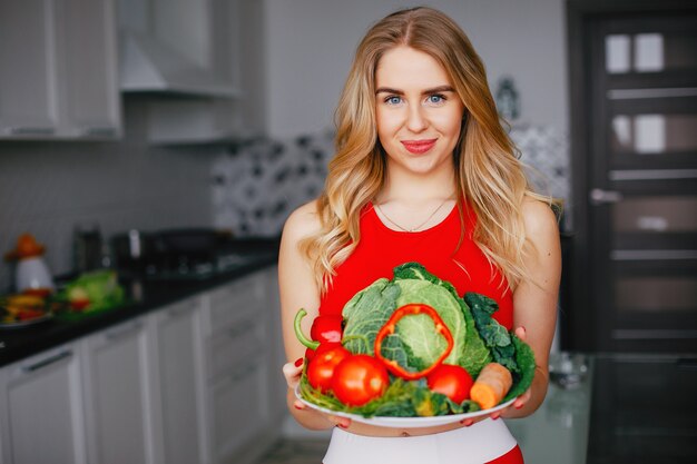 Sportenmeisje in een keuken met groenten
