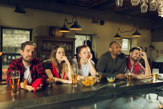 Sportfans juichen in bar, pub en drinken bier terwijl kampioenschap, competitie gaat