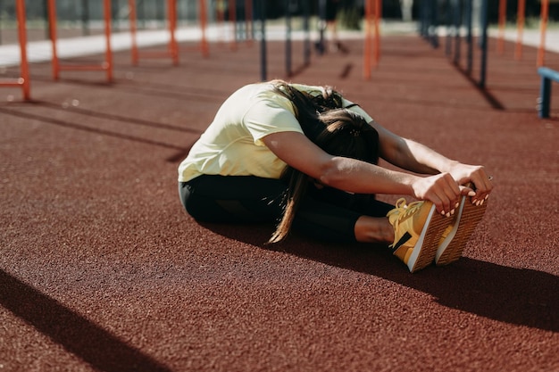 Gratis foto sportieve jonge brunette die spieren uitrekt na training