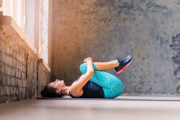 Sportieve jonge vrouw die op yogamat uitoefent