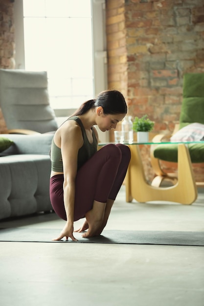 Sportieve jonge vrouw die thuis yoga beoefent