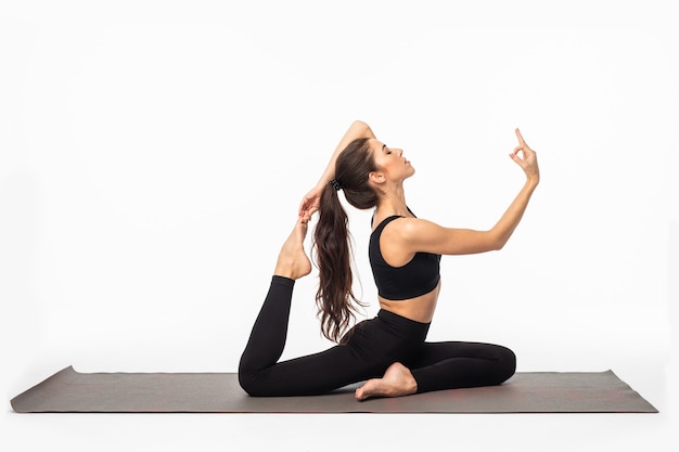 Sportieve jonge vrouw die yoga beoefent geïsoleerd op een witte ondergrond - concept van gezond leven en natuurlijk evenwicht tussen lichaam en mentale ontwikkeling