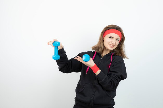 Sportieve jongedame permanent en blauwe halters te houden. Hoge kwaliteit foto