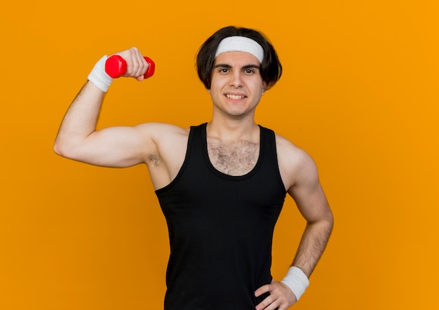 Sportieve jongeman met sportkleding en hoofdband met halter in de hand die oefeningen doet die zelfverzekerd staan