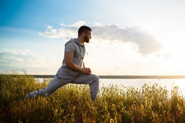 Sportieve jongeman opleiding in veld bij zonsopgang.