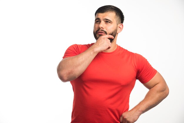 Sportieve man in rood shirt demonstreert zijn armspieren en ziet er zelfverzekerd uit