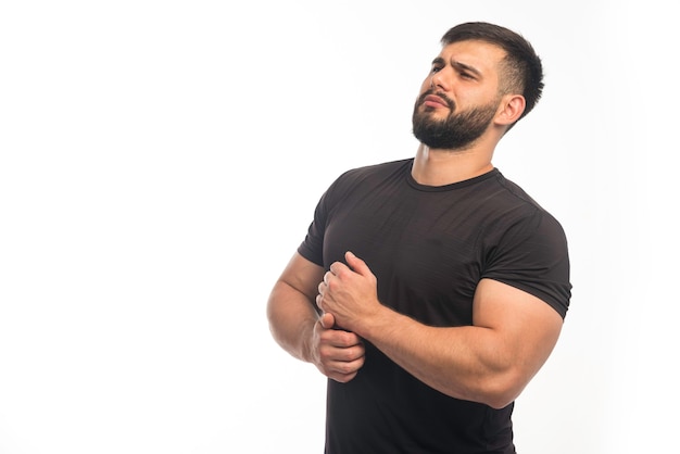 Sportieve man in zwart shirt demonstreren zijn armspieren.