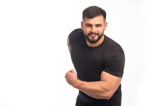 Sportieve man in zwart shirt met zijn biceps.